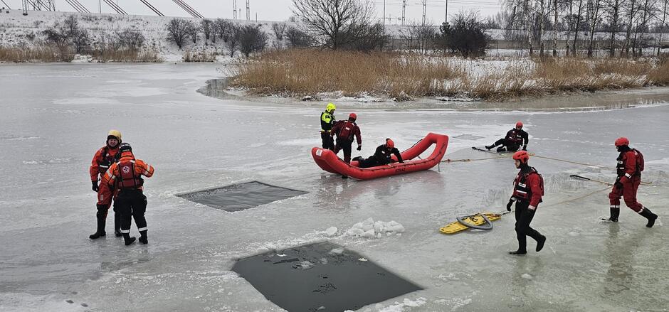 na zdjęciu strażacy w specjalnych ocieplanych strojach, ćwiczą na zamarzniętej rzece