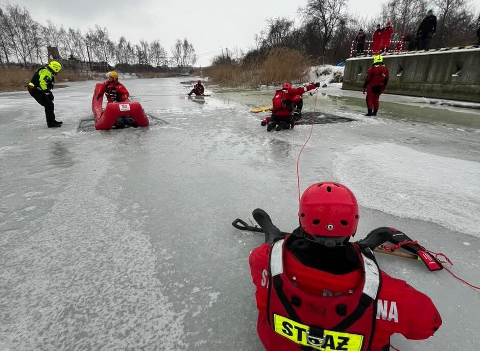 na zdjęciu kilku strażaków ćwiczących na zamarzniętej tafli rzeki