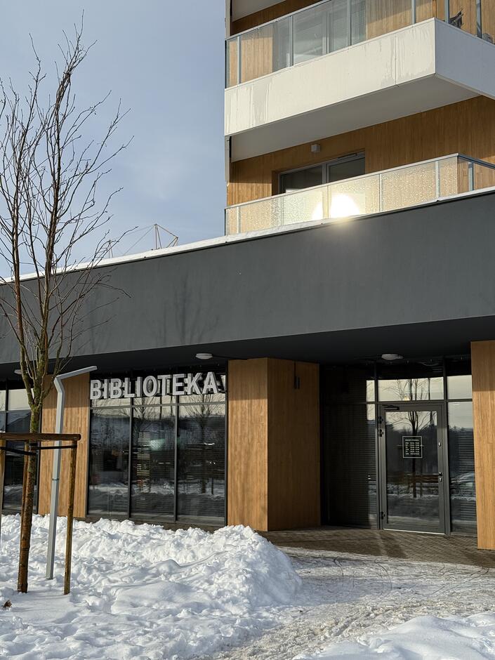 na zdjęciu nowoczesny budynek o brązowo czarnej elewacji, na parterze widać duże szerokie okno a nad nim napis biblioteka