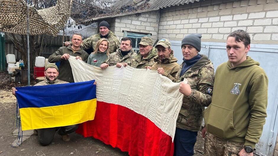 Zdjęcie grupy osób które trzymają dwie flagi - polską i ukraińską 