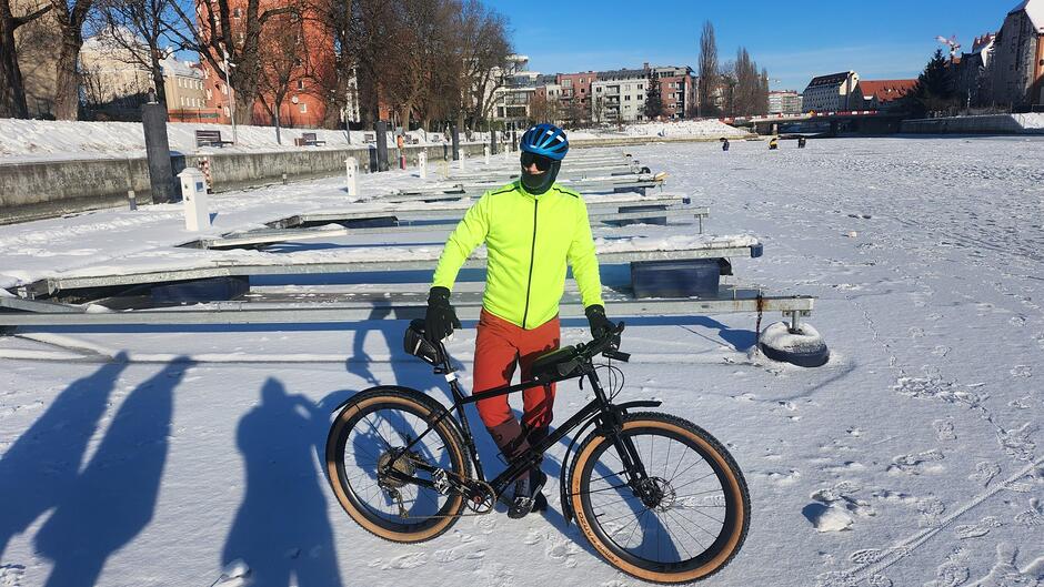 Kolarz stoi z rowerem na lodowej tafli
