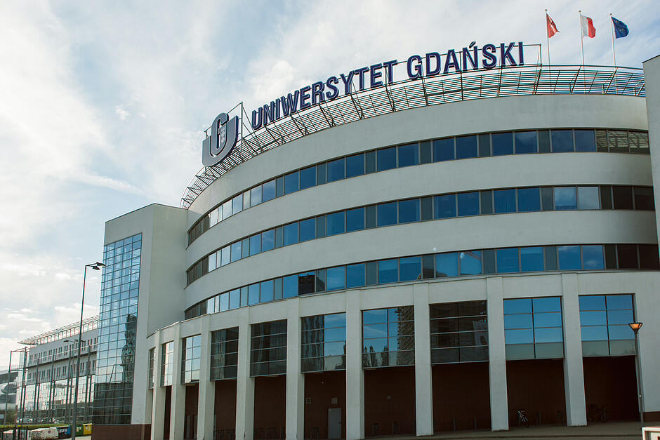 Główny budynek UG, w tle powiewają flagi UE, Gdańska i Polski.