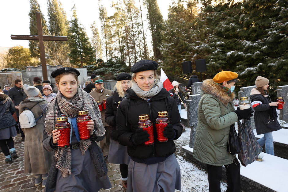 Na pierwszym planie dwie nastolatki z zapalonymi zniczami w kwaterze akowskiej na cmentarzu Łostowickim