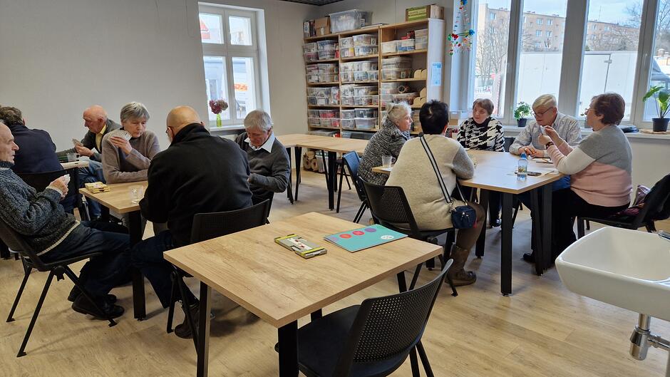 Starsi ludzie przy stolikach grają w brydża