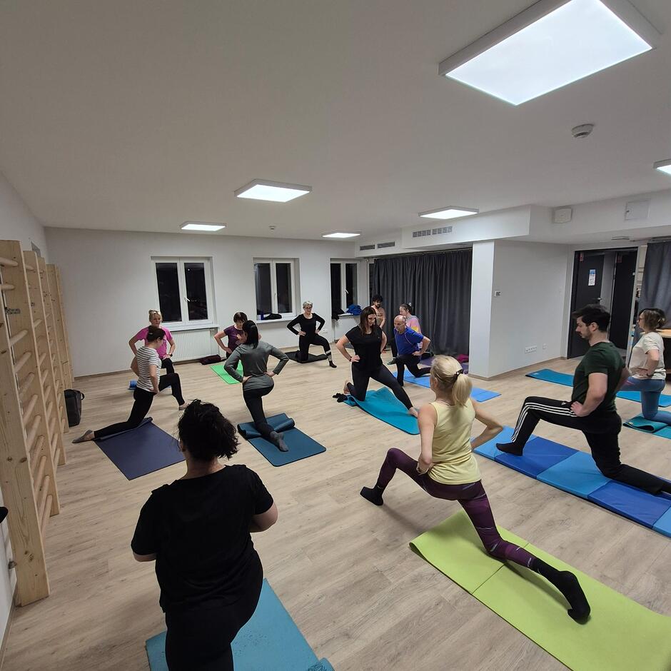 Kilka pań i jeden pan klęczących na matach do jogi podczas ćwiczeń