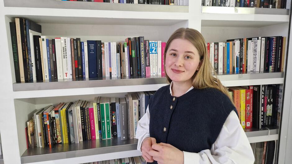 Młoda dziewczyna na tle regału z książkami o sztuce