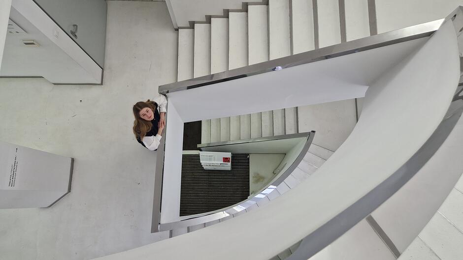 Widok z góry schodów na dziewczynę. Wszystko utrzymane w bieli z akcentami metalu