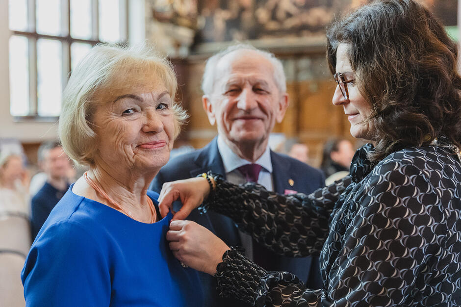 kobieta i mężczyzna odbierają medal. Są elegancko ubrani, kobieta patrzy prosto w obiektyw i się uśmiecha