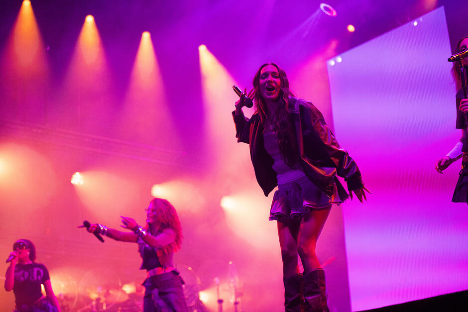 Trzy kobiety śpiewają na scenie.