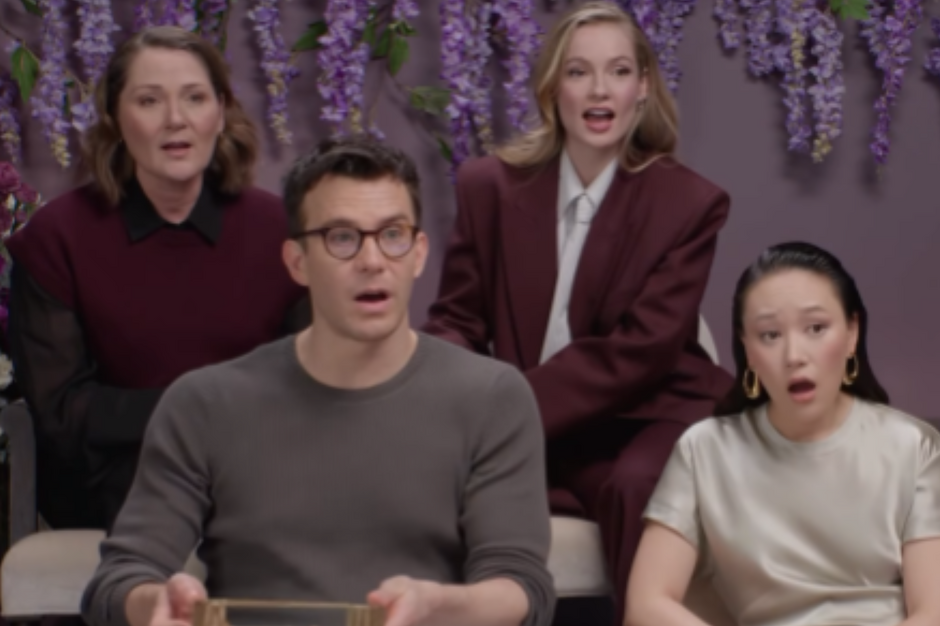 Cztery osoby siedzą, jedna z nich trzyma w ręku małe pudełko. Wyglądają na zaskoczonych