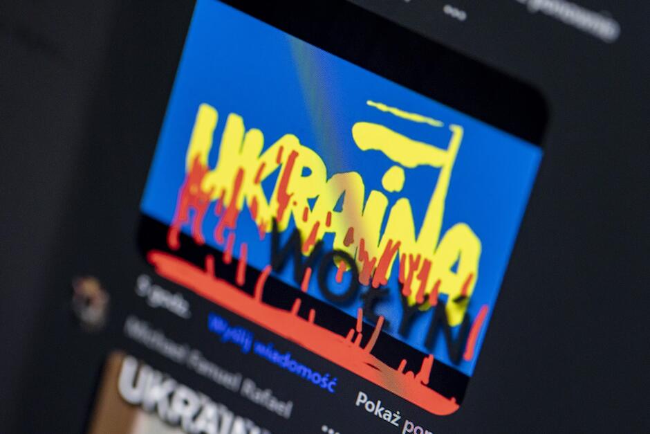 Ilustracja przedstawiająca zachlapaną na czerwono flagę Ukrainy i hasło Wołyń