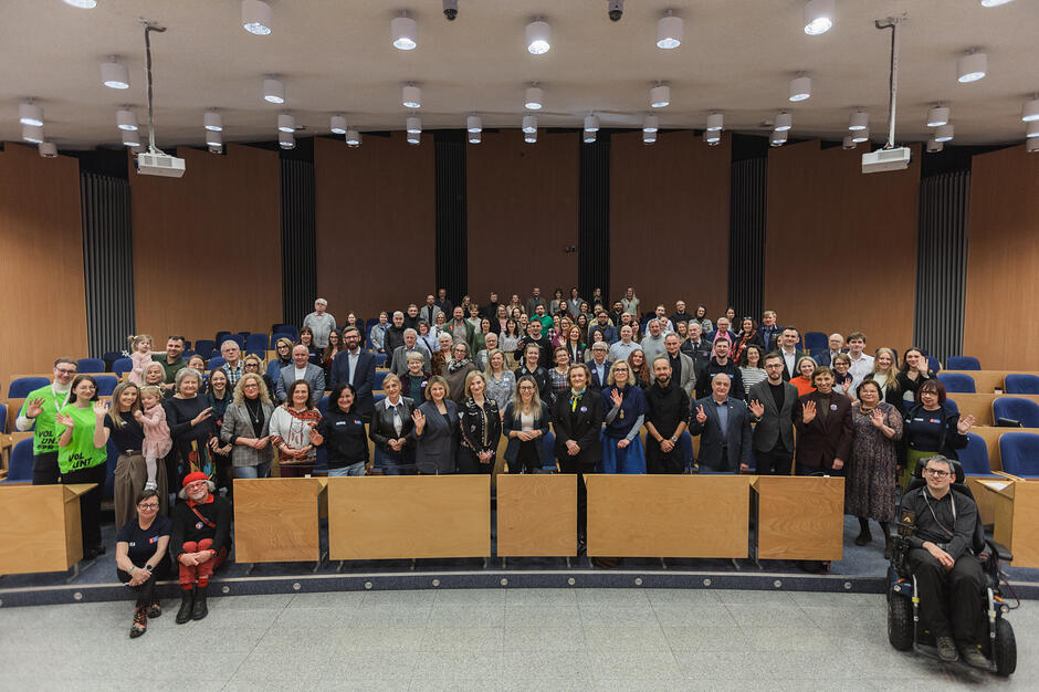 Ponad sto ludzi pozuje do zdjęcia w sali plenarnej.