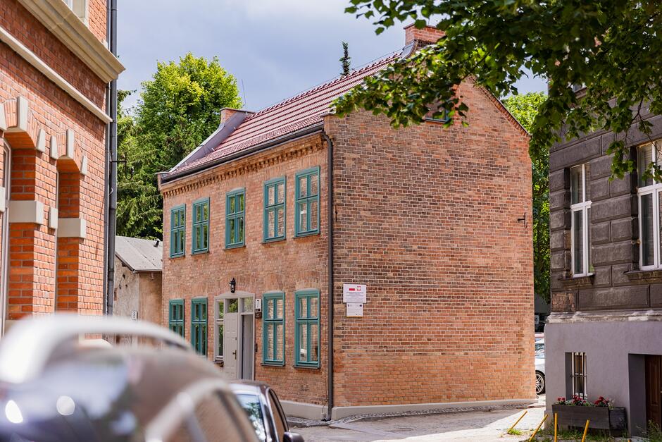 Ceglany piętrowy budynek z zielonymi oknami