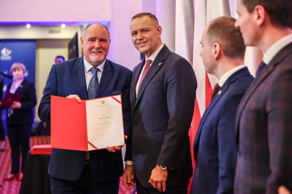 Dwa mężczyźni - ten po lewej prezentuje otrzymany dokument