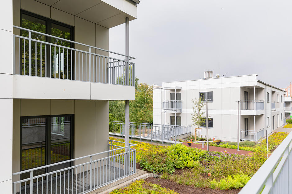 na zdjęciu dwa niewysokie bloki mieszkalne o jasnej elewacji