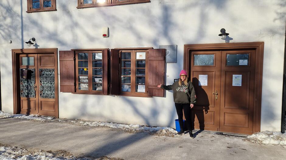 Dziewczyna w różowej wełnianej czapce i okularach przed budynkiem 