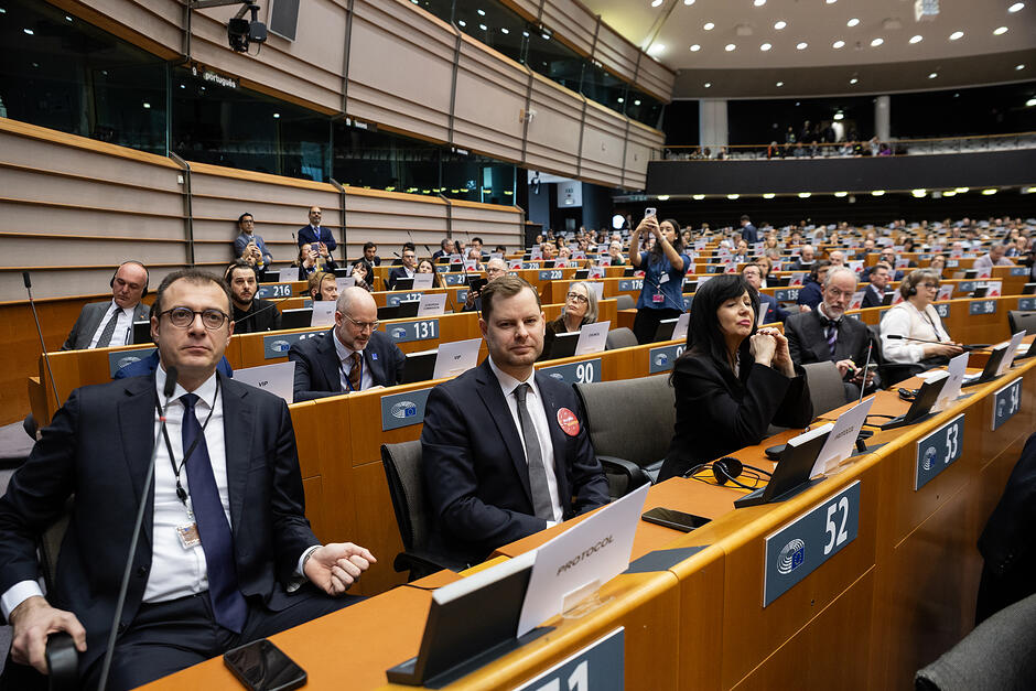 Ludzie siedzą w ławach w sali obrad.
