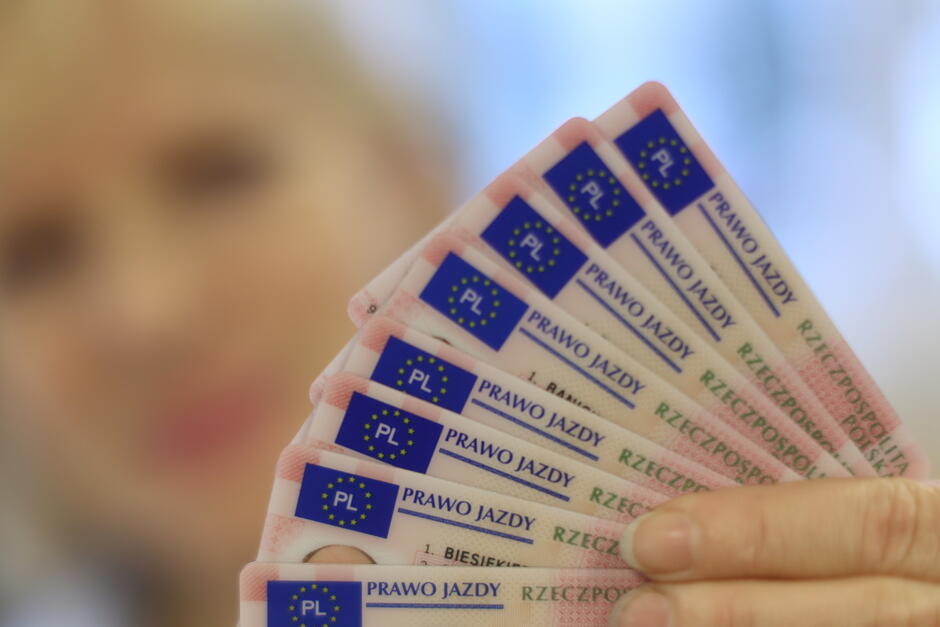 Dłoń trzyma kilka praw jazdy ułożonych jak karty do gry