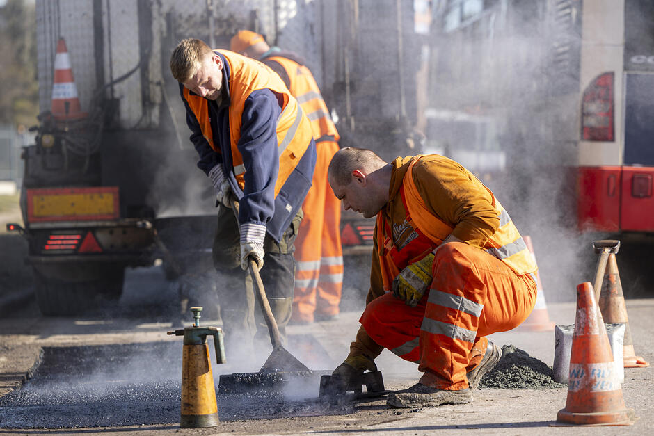 na zdjęciu dwóch robotników, uzupełniają ubytki w jezdni