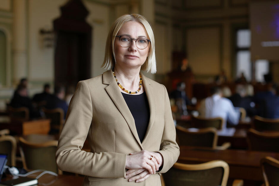 Zdjęcie portretowe kobiety w średnim wieku. Blond włosy od pół szyi. Okulary. Uśmiech