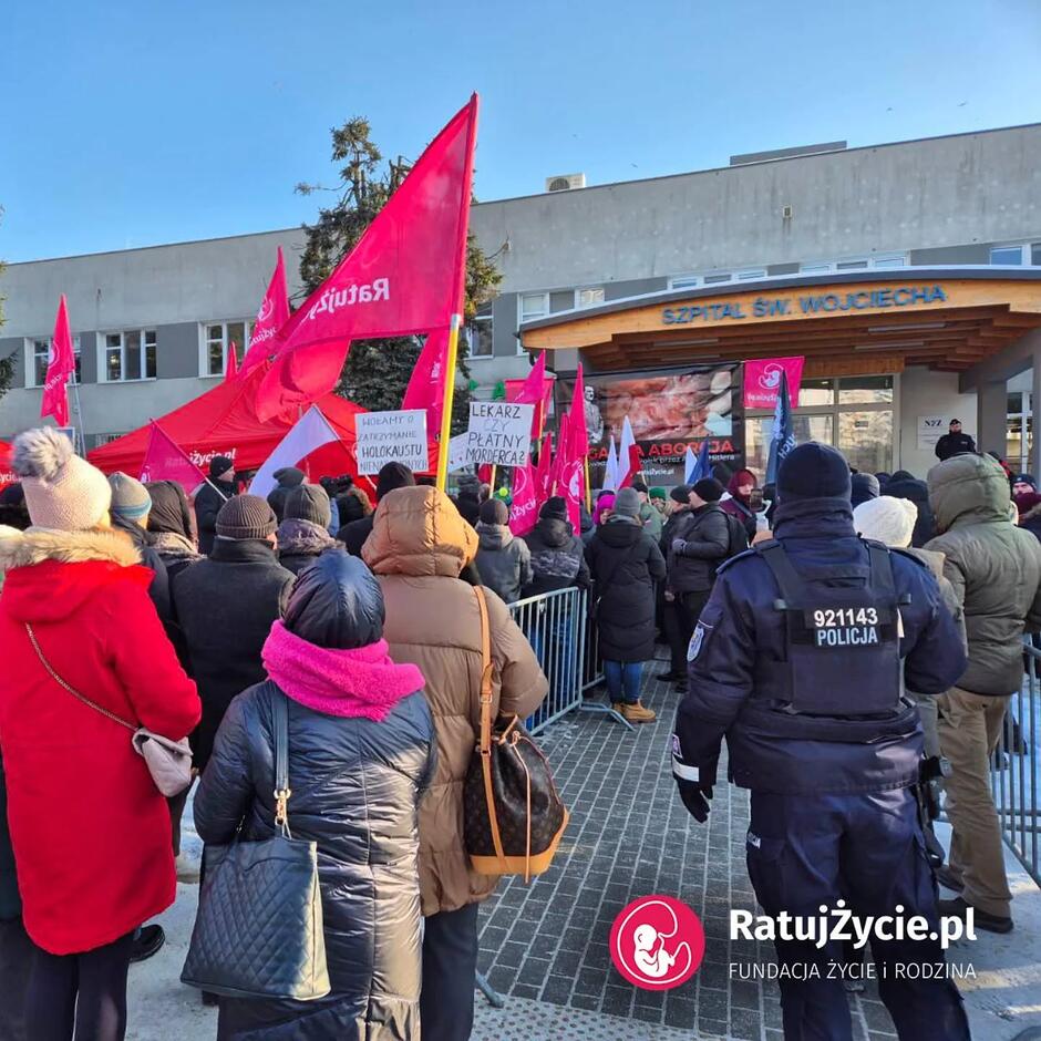 Grupa osób z transparentami i flagami przed szpitalem