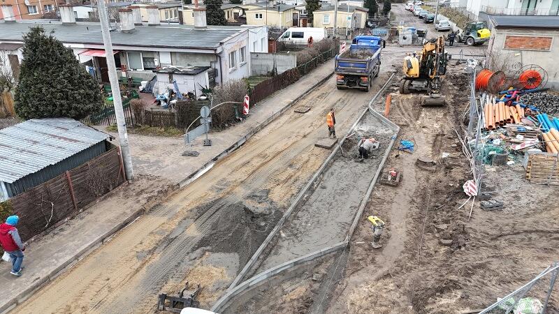 zdjęcie z drona, widać rozkopaną, przebudowywaną ulicę, jest głównie grunt, widać robotników i koparki