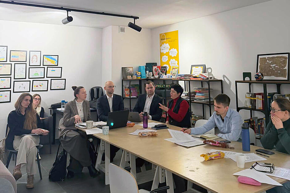 Kilka osób siedzi przy stole i rozmawia.