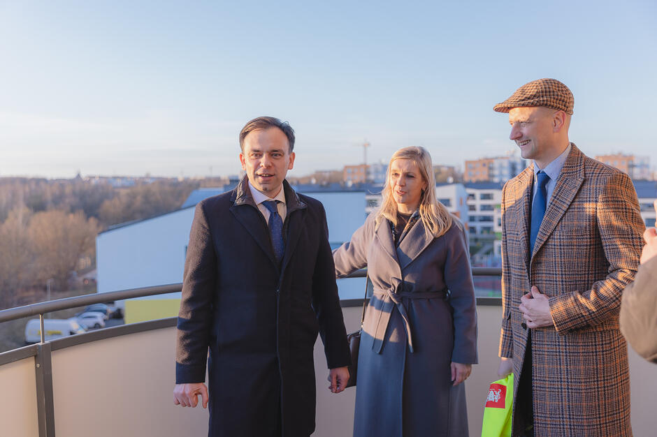 Trzy osoby rozmawiają na balkonie budynku