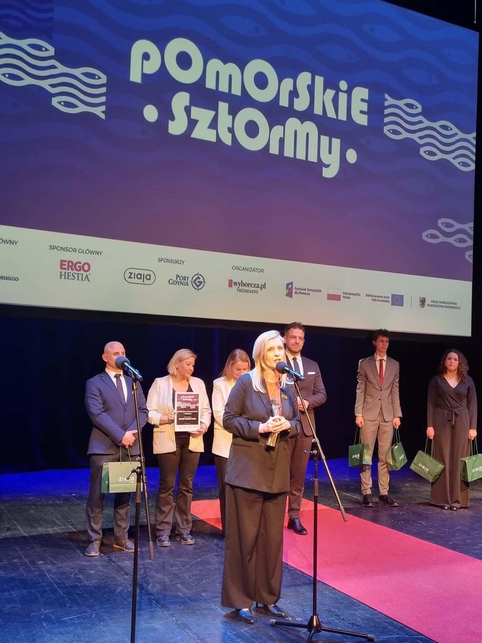 Kobieta ze statuetką stojąca przed mikrofonem