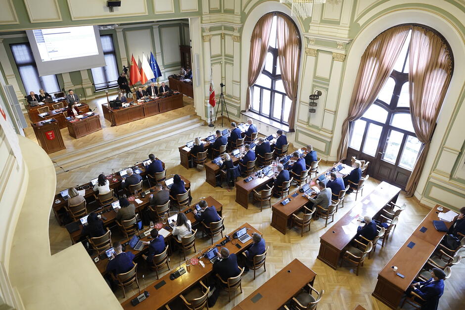 Sala obrad pokazana z góry, z galerii dla publiczności. Radni siedzą w dole przy ławach