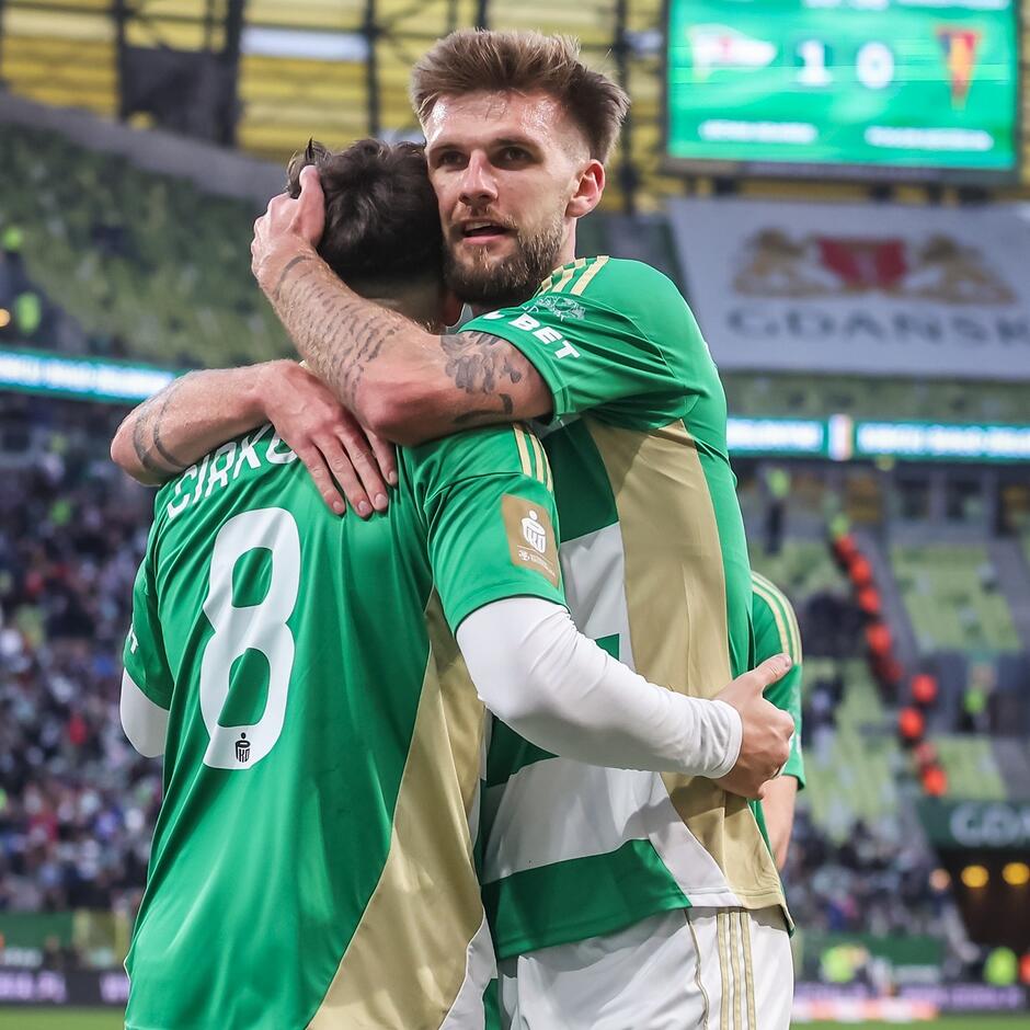 Dwaj zawodnicy na boisku w radosnym uścisku