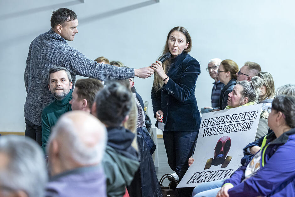 na zdjęciu kobieta w czarnym stroju mówi do mikrofonu który podsuwa jej mężczyzna stojący obok