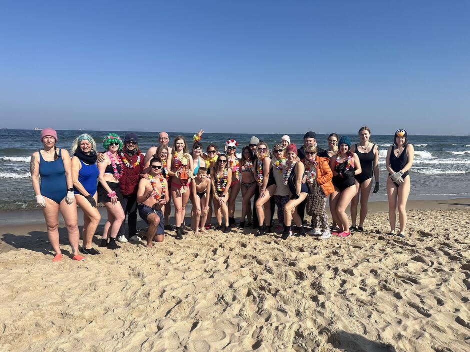 Ludzie w strojach kąpielowych stoją na tle morza