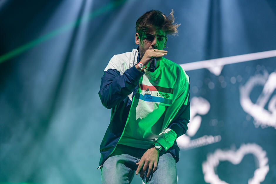 Młody mężczyzna z mikrofonem, na scenie