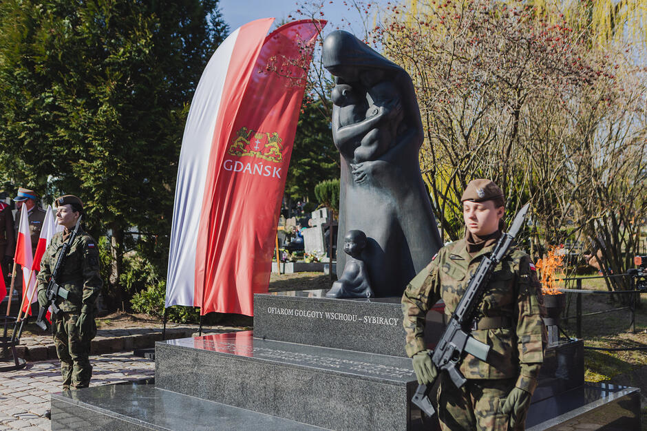 Warta honorowa wojskowa przy pomniku Golgota Wschodu, obok pomnika duża pionowa flaga z herbem miasta i napisem Gdańsk