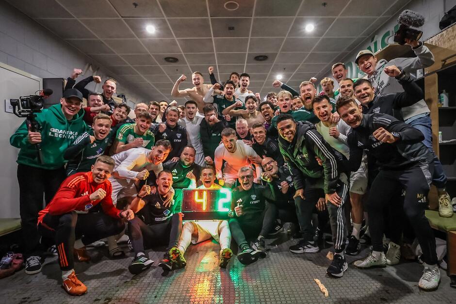 Grupa około 30 mężczyzn pozuje grupowo na wspólnym zdjęciu, w entuzjastycznych nastrojach 