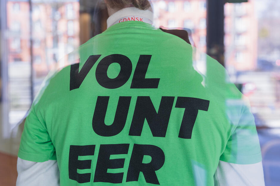 Plecy człowieka w zielonej koszulce z napisem volunteer .