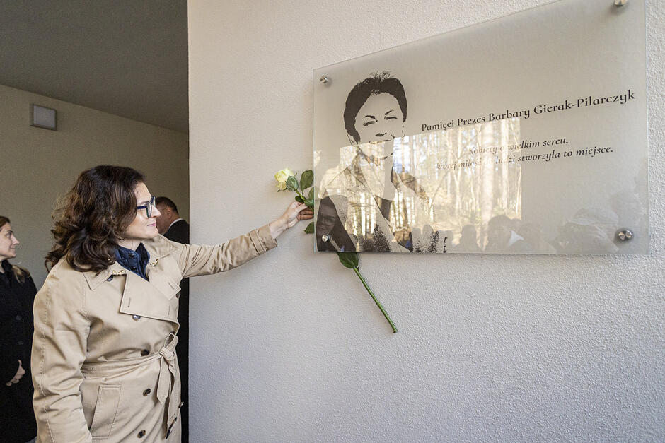 Prezydent Dulkiewicz zatyka różę z lewej strony tablicy, która jest przeźroczysta