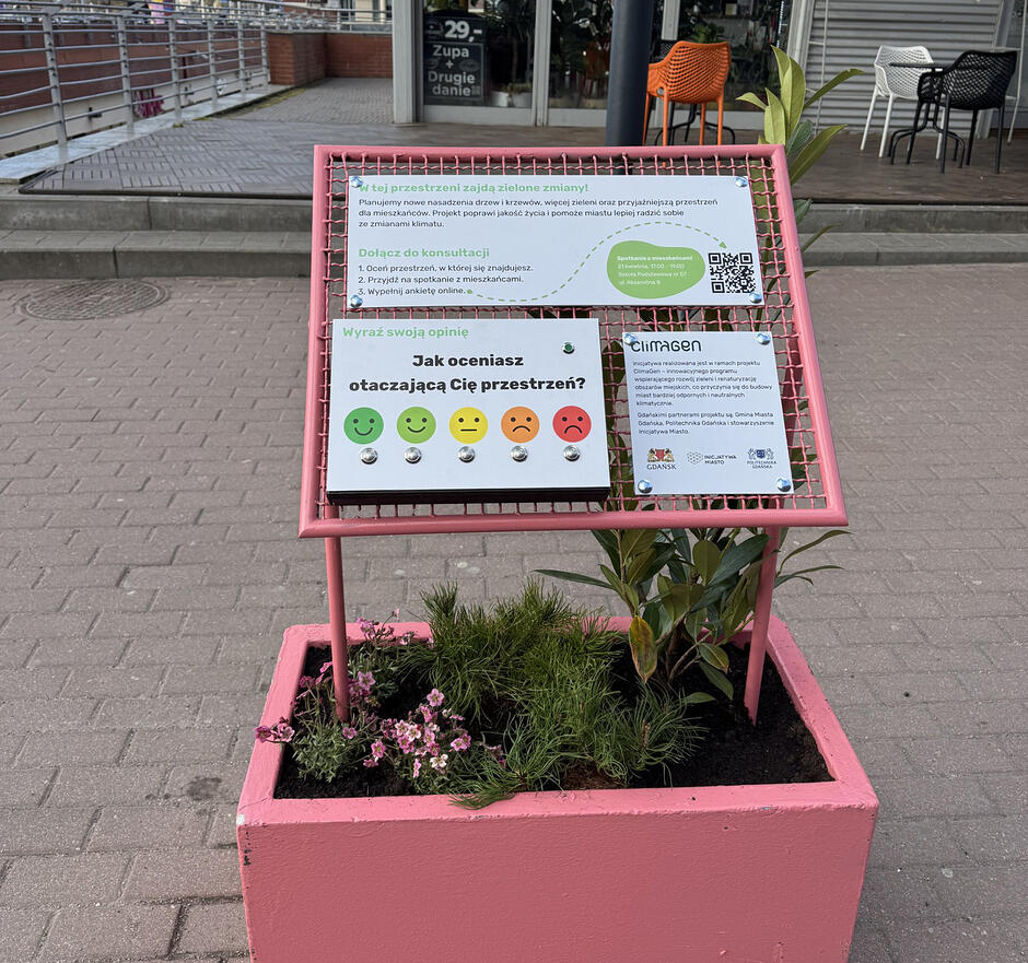 Różowa donica z tablicą na placu miejskim.