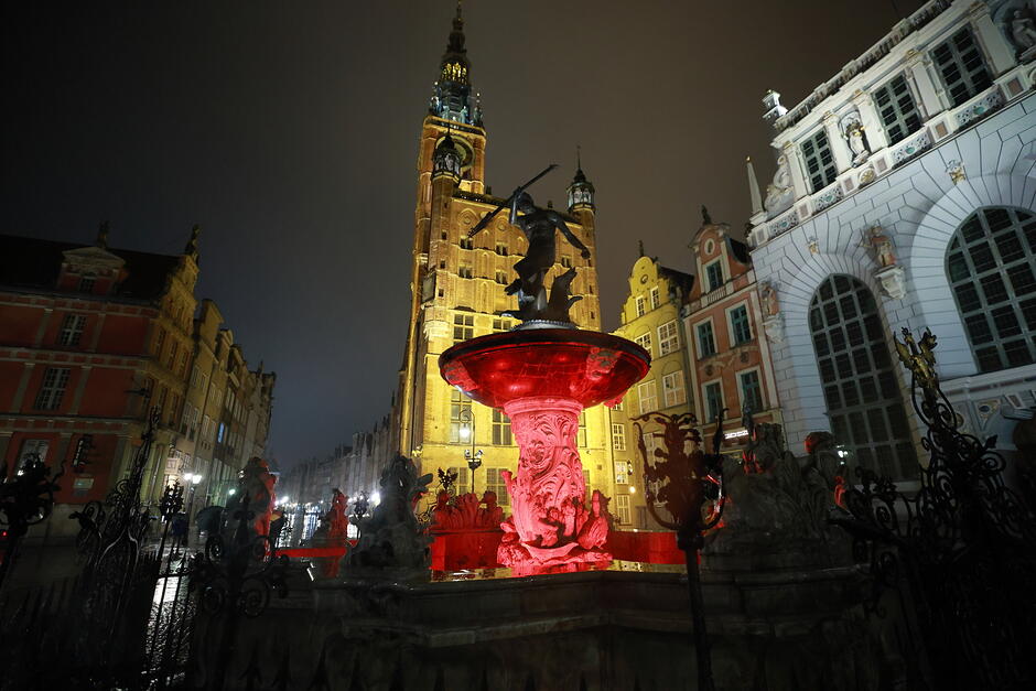 Fontanna Neptuna na starym mieście podświetlona na czerwono.