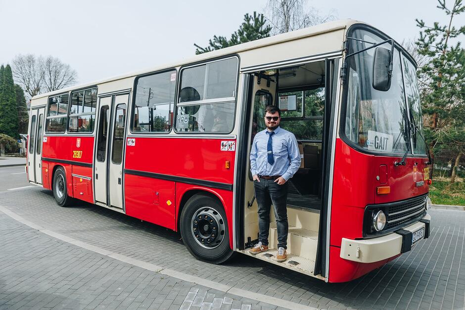 Zabytkowy czerwony Ikarus. W przednim wejściu stoi kierowca, który patrzy prosto w obiektyw