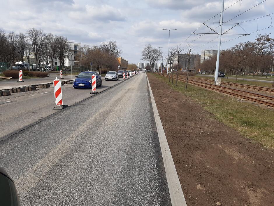 na zdjęciu fragment asfaltowej jezdni, widać biało czerwone znaki drogowe