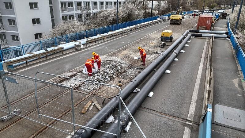 zdjęcie z drona, widać trzech robotników w roboczych strojach pracujących na remontowanym moście