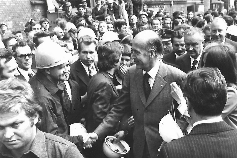 Prezydent pośród wielu osób, niektóre z nich mają robotnicze kaski