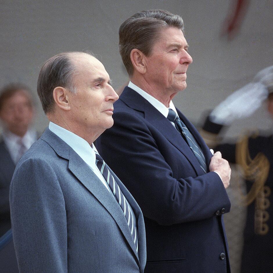 Mitterand i Reagan podczas uroczystości - stoją na baczność, ramię w ramię