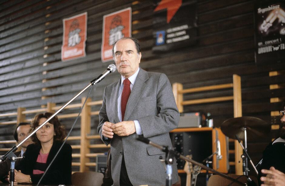 Mężczyzna stoi przy stole, przemawia