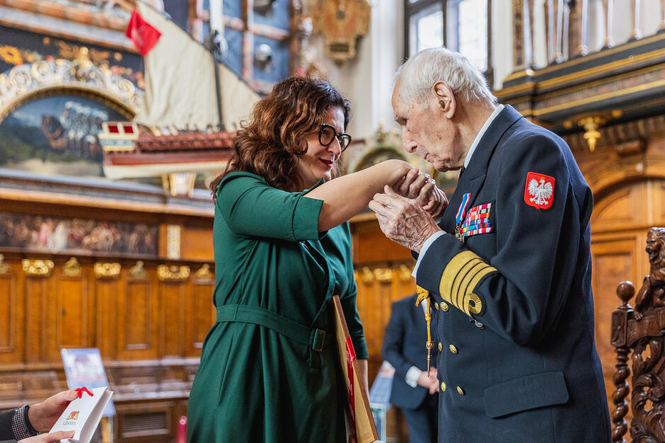 Prezydent Dulkiewicz po lewej, kmdr Rakowski po prawej - całuje prezydent Gdańska w rękę