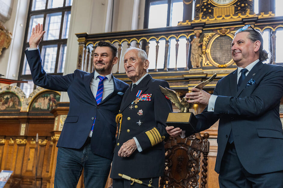 Trzej mężczyźni stoją, pośrodku Roman Rakowski