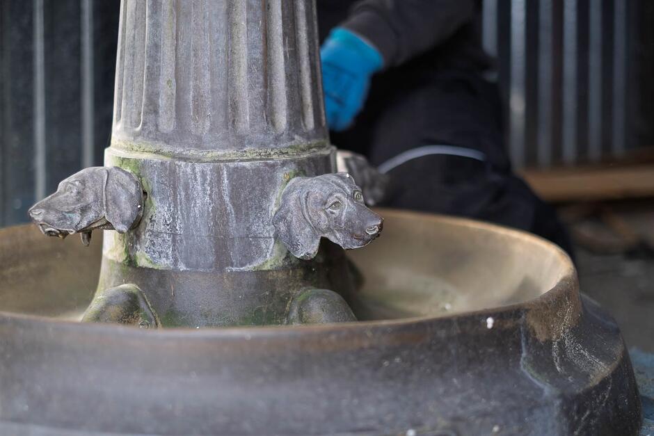 Detale metalowej fontanny w formie psich głów.