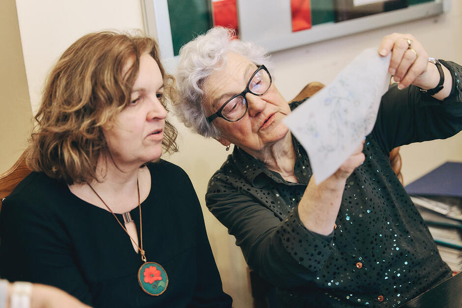 Dwie kobiety pokazują sobie hafty 